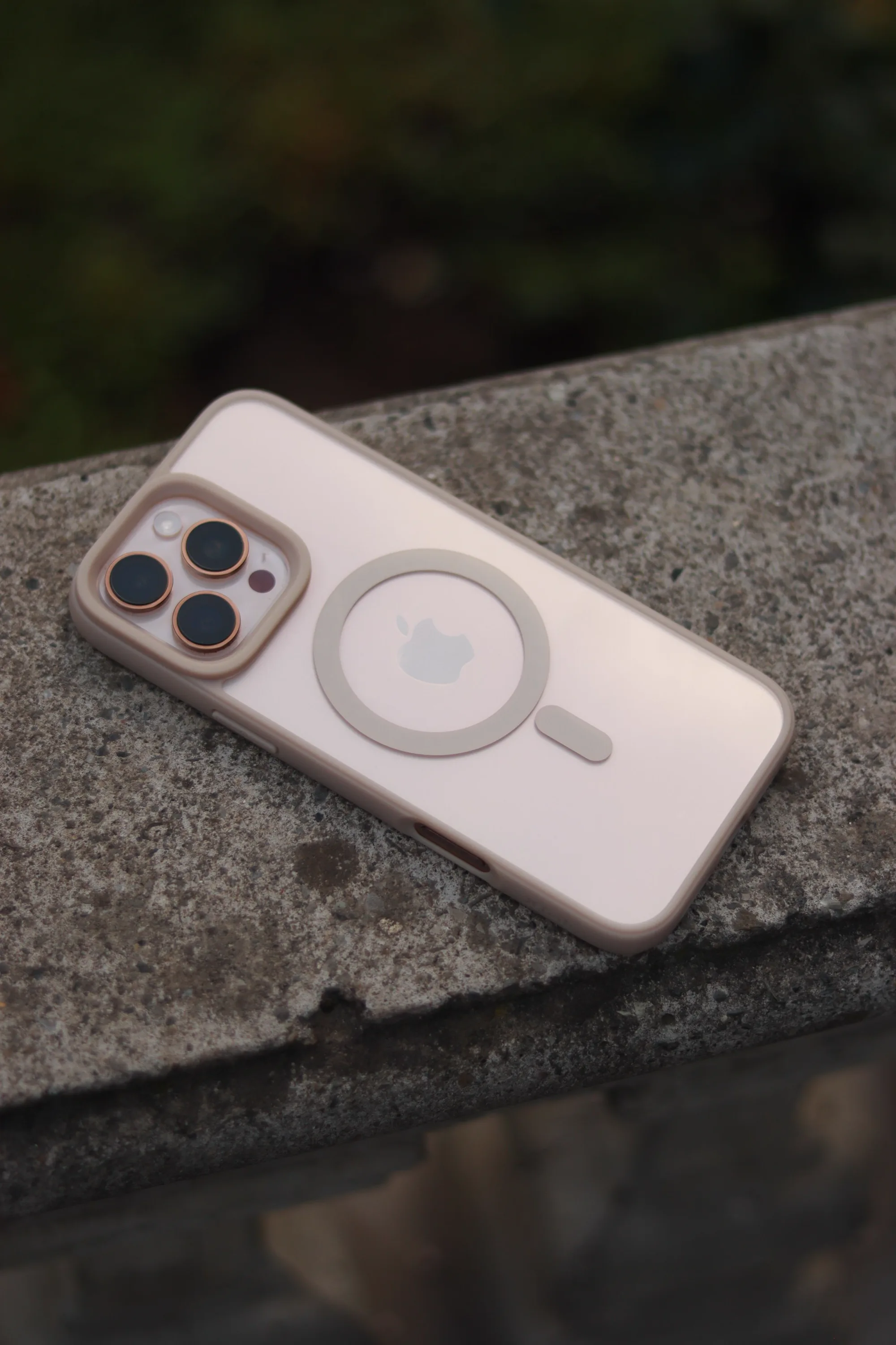 A smartphone with a MagSafe charger on a stone surface