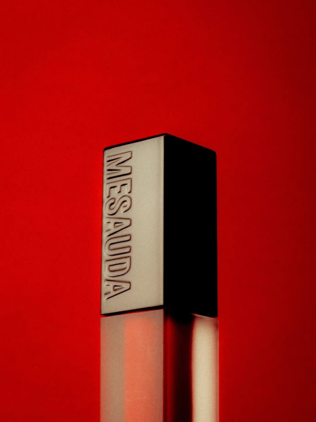 A cosmetic product against a vibrant red background